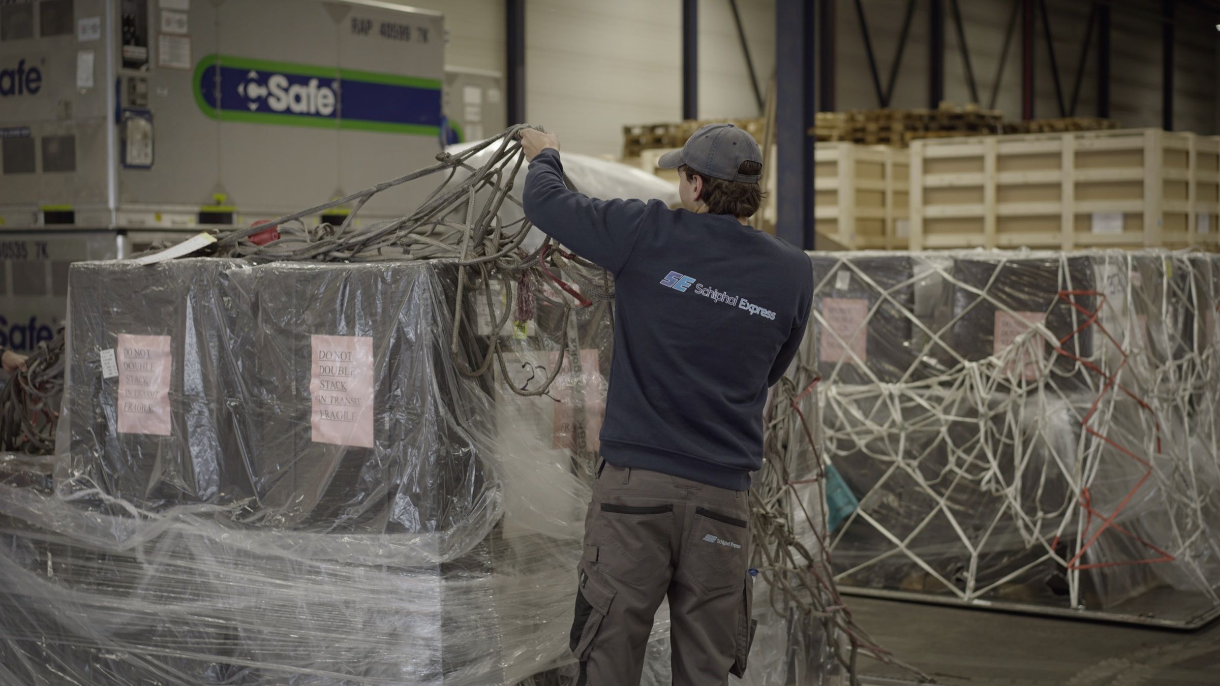 Medewerker van Schiphol Express haalt het net van een luchtvrachtpallet